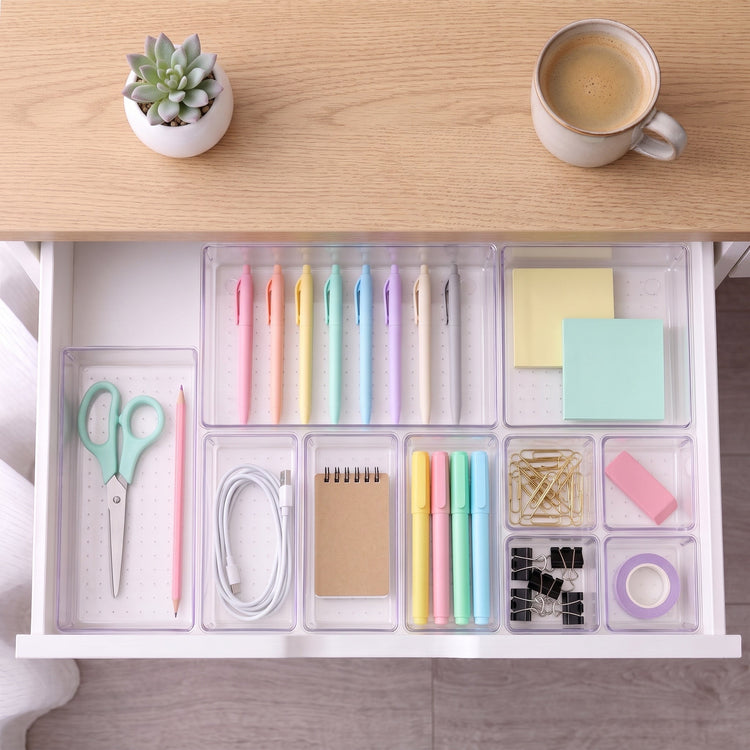 Clear trays organizing stationery in a desk drawer