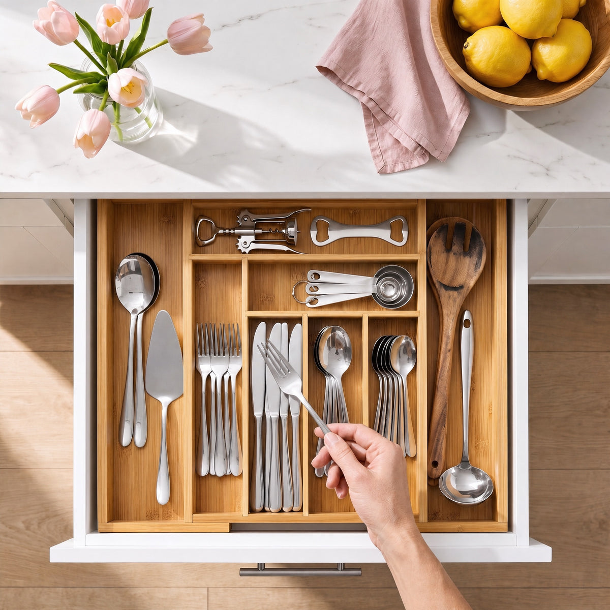 Hand taking a fork from the bamboo cutlery organizer in a kitchen drawer