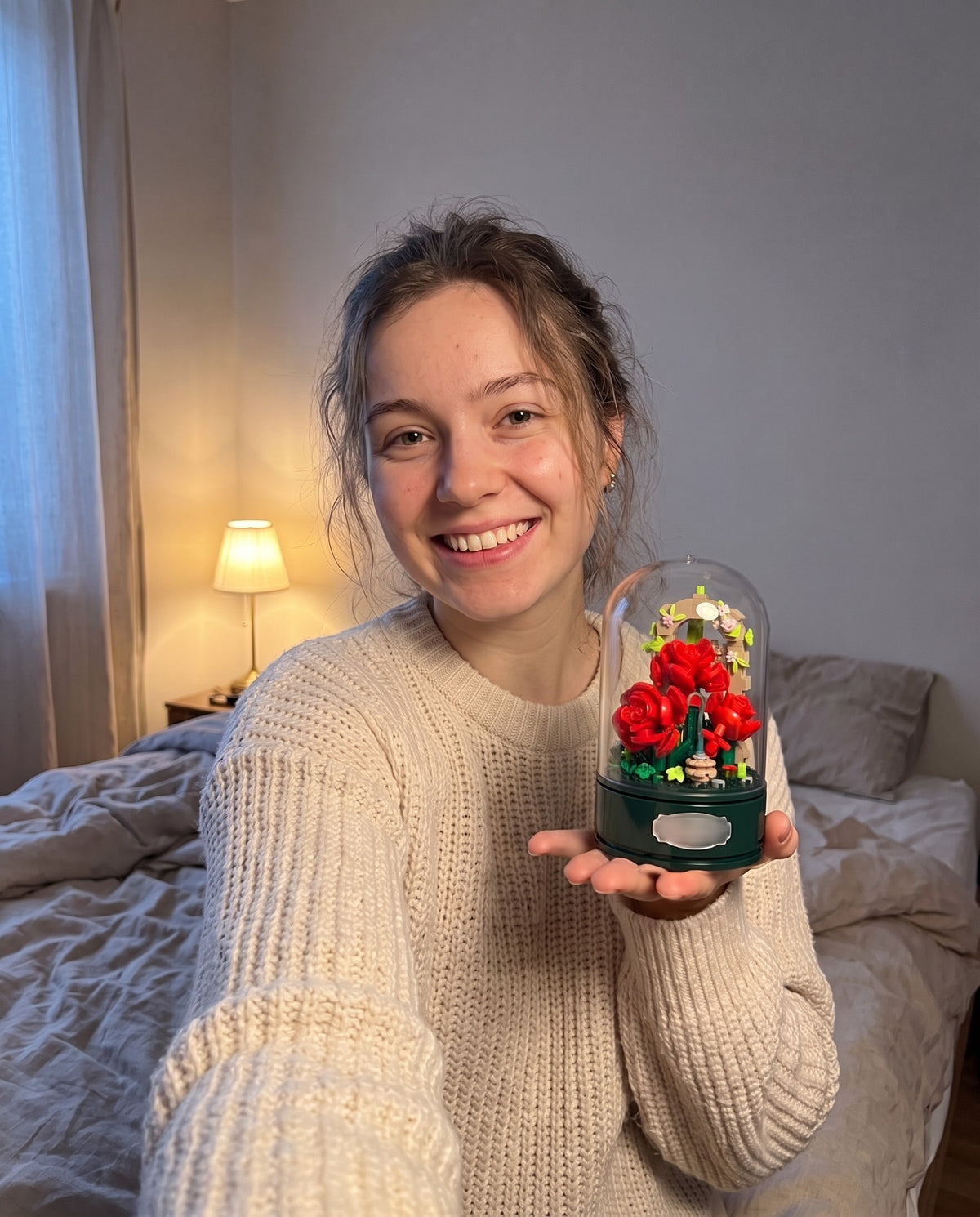 A young woman smiling in a selfie, holding the rose garden music box on her palm