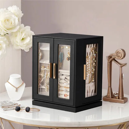 Black rotating jewelry cabinet with clear doors on a marble side table, rings, earrings and necklaces visible inside